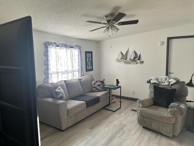 living room featuring ceiling fan, a textured ceiling, and light wood-type flooring