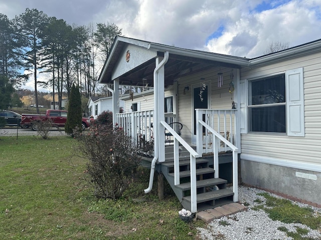 entrance to property featuring a porch and a yard