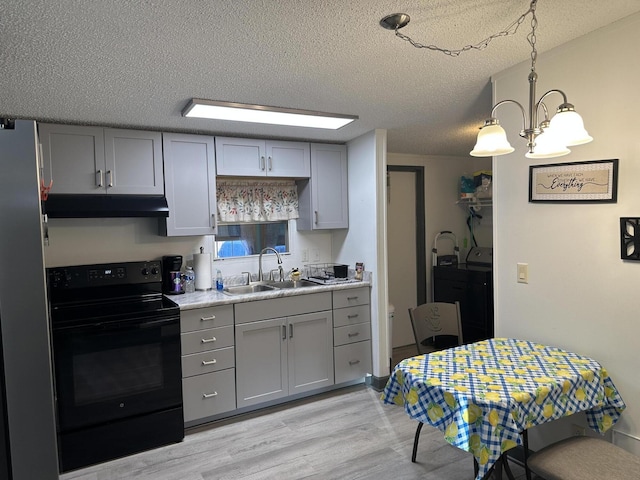 kitchen featuring sink, decorative light fixtures, washing machine and dryer, gray cabinets, and black / electric stove