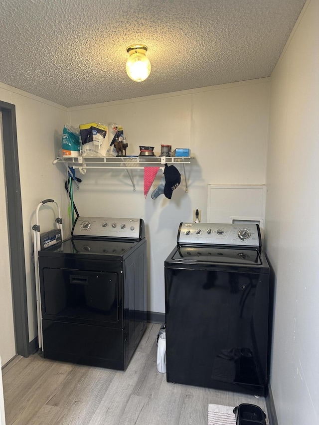 washroom featuring separate washer and dryer, light hardwood / wood-style floors, and a textured ceiling