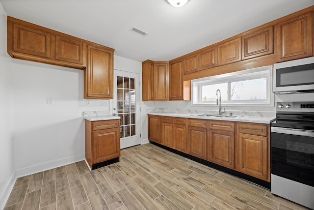 kitchen with light stone countertops, appliances with stainless steel finishes, and sink