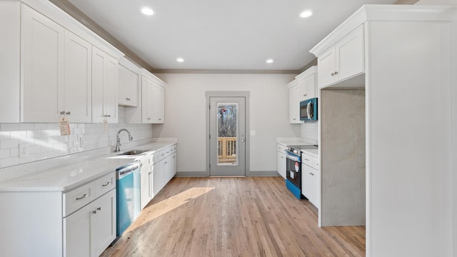 kitchen with appliances with stainless steel finishes, light hardwood / wood-style floors, sink, and white cabinets