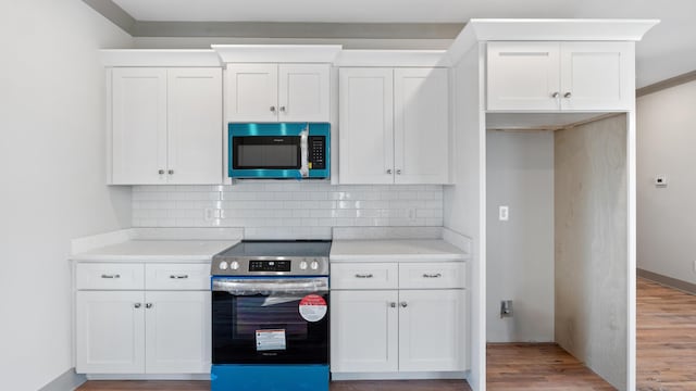 kitchen with white cabinets, electric range, backsplash, and light hardwood / wood-style flooring