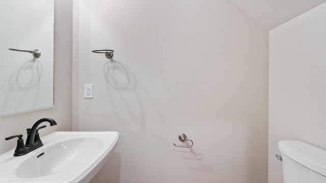 bathroom featuring lofted ceiling, toilet, and sink