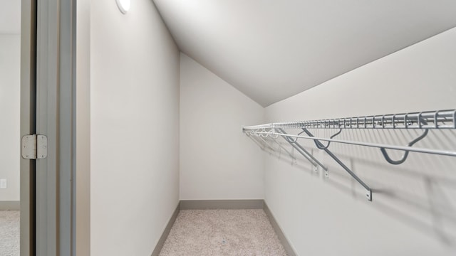 spacious closet with lofted ceiling and light colored carpet