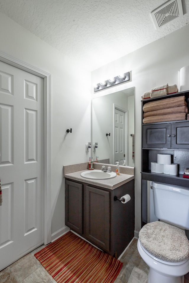 bathroom featuring vanity, a textured ceiling, and toilet