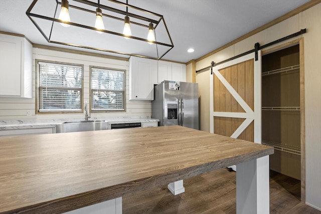 kitchen with a barn door, white cabinets, pendant lighting, and stainless steel refrigerator with ice dispenser