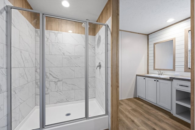 bathroom featuring vanity, wood-type flooring, a textured ceiling, and walk in shower