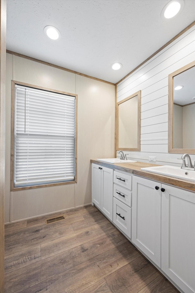 bathroom featuring crown molding, vanity, wood-type flooring, and wood walls