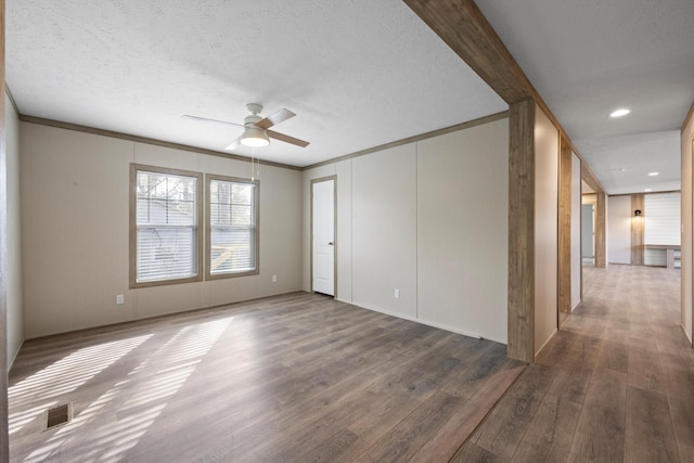 empty room with a textured ceiling, ceiling fan, dark hardwood / wood-style floors, and ornamental molding