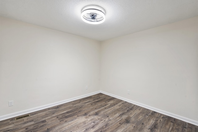 empty room with dark hardwood / wood-style flooring and a textured ceiling