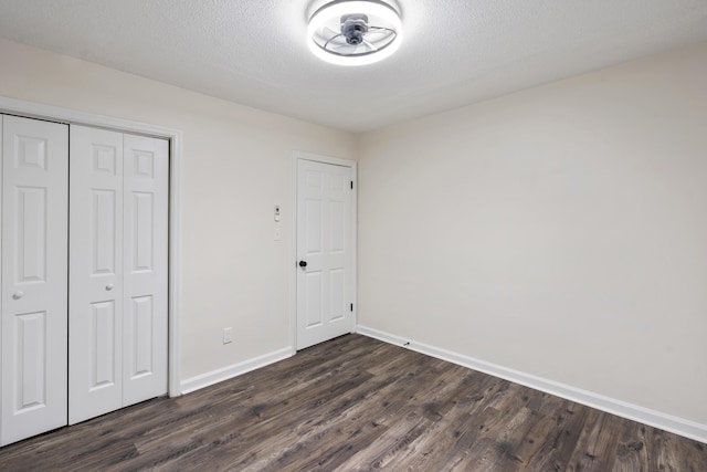 unfurnished bedroom featuring dark hardwood / wood-style flooring, a textured ceiling, and a closet