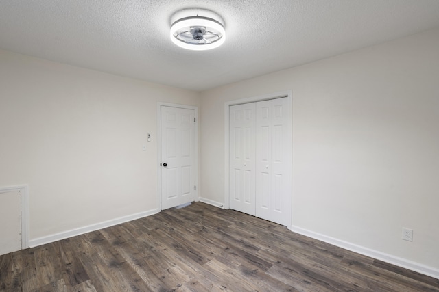 unfurnished bedroom featuring a textured ceiling, dark hardwood / wood-style floors, and a closet