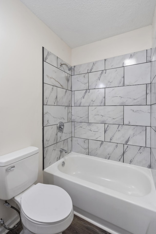 bathroom featuring tiled shower / bath combo, toilet, wood-type flooring, and a textured ceiling