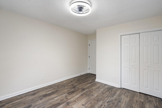 unfurnished bedroom with a textured ceiling, a closet, and dark hardwood / wood-style floors