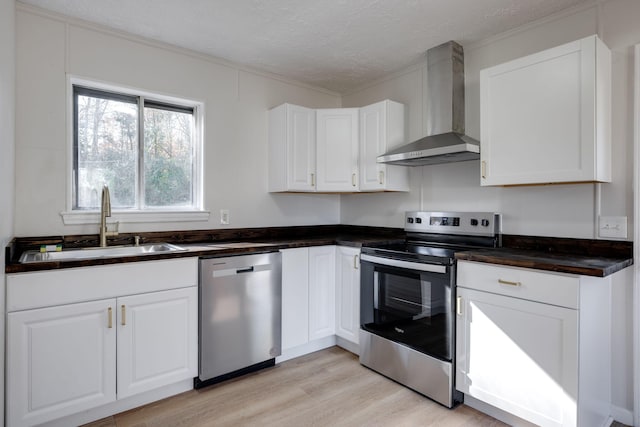 kitchen with stainless steel appliances, white cabinetry, a textured ceiling, wall chimney exhaust hood, and light hardwood / wood-style floors