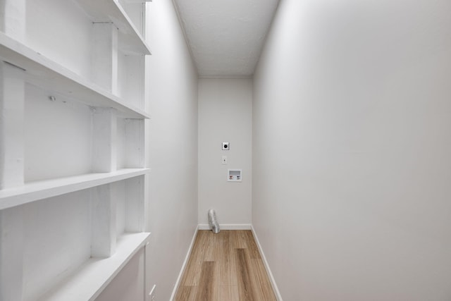 washroom featuring electric dryer hookup, hookup for a washing machine, light hardwood / wood-style floors, and a textured ceiling