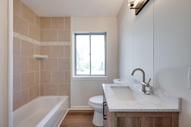 full bathroom featuring toilet, wood-type flooring, vanity, and tiled shower / bath