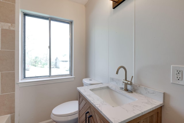 bathroom featuring toilet, vanity, and a healthy amount of sunlight