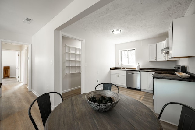 dining room featuring a textured ceiling, light hardwood / wood-style floors, built in features, and sink