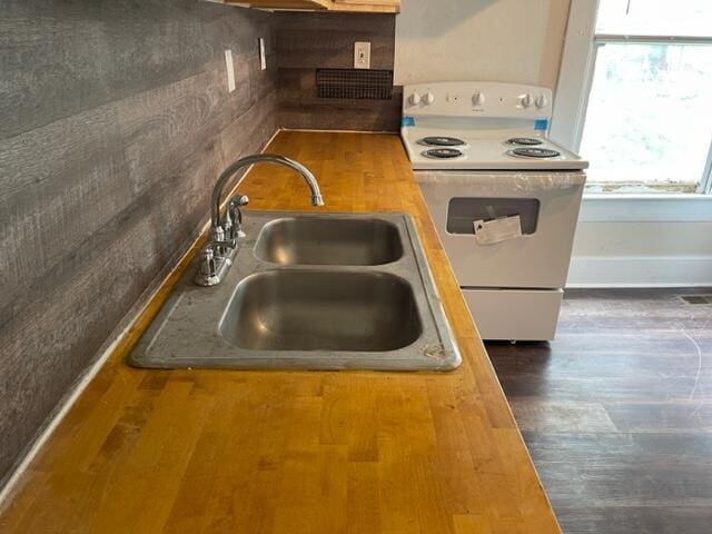 kitchen with white electric stove, butcher block countertops, sink, and dark hardwood / wood-style floors