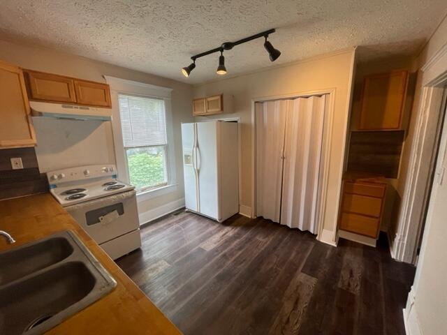 kitchen featuring dark hardwood / wood-style floors, sink, a textured ceiling, and white appliances