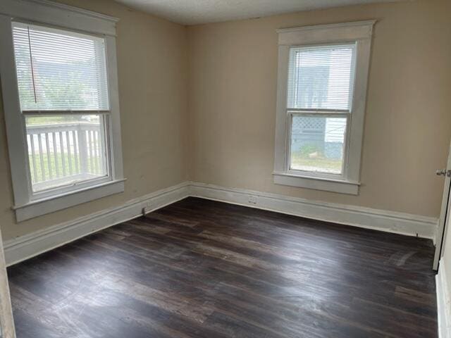 unfurnished room featuring plenty of natural light and dark hardwood / wood-style floors