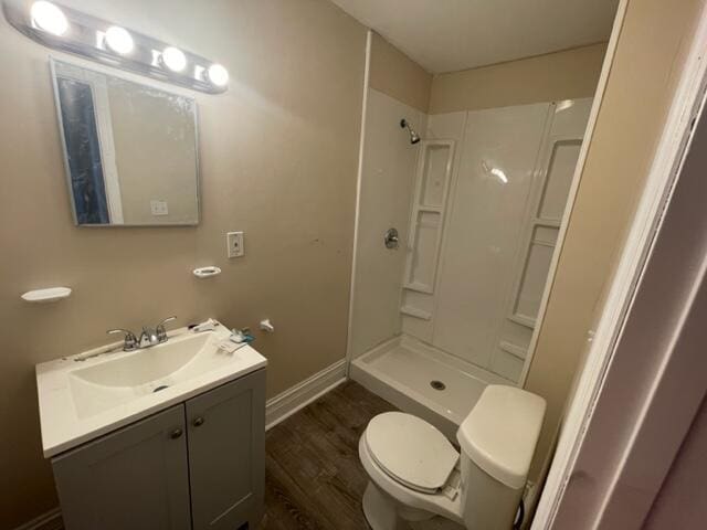 bathroom featuring vanity, wood-type flooring, toilet, and walk in shower