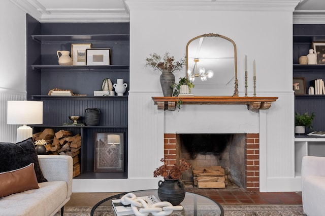 living room featuring a fireplace, crown molding, built in features, and an inviting chandelier