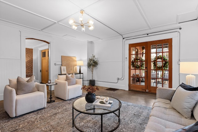 living room with a chandelier, concrete floors, and ornamental molding