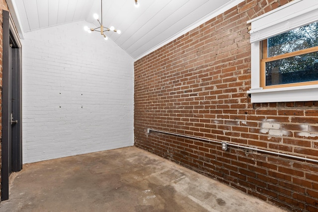 corridor with a chandelier, concrete floors, lofted ceiling, and brick wall