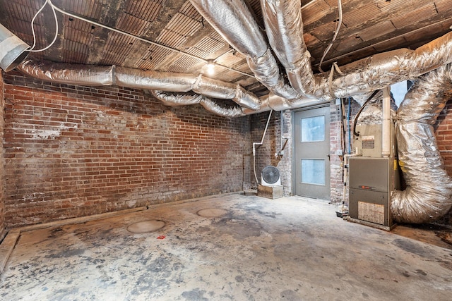 basement with heating unit and brick wall