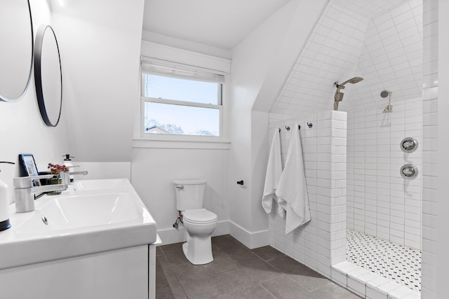 bathroom with tile patterned flooring, vanity, tiled shower, and toilet