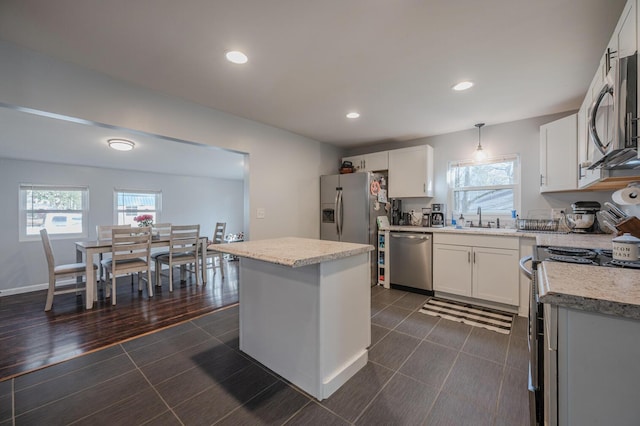 kitchen with a center island, white cabinets, decorative light fixtures, dark hardwood / wood-style flooring, and stainless steel appliances