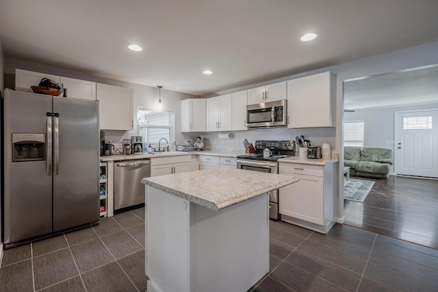 kitchen featuring a center island, dark wood-type flooring, white cabinets, hanging light fixtures, and stainless steel appliances