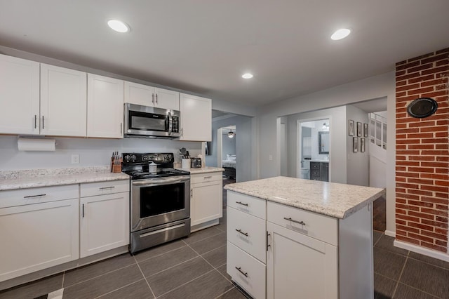 kitchen with light stone countertops, white cabinetry, a center island, and stainless steel appliances