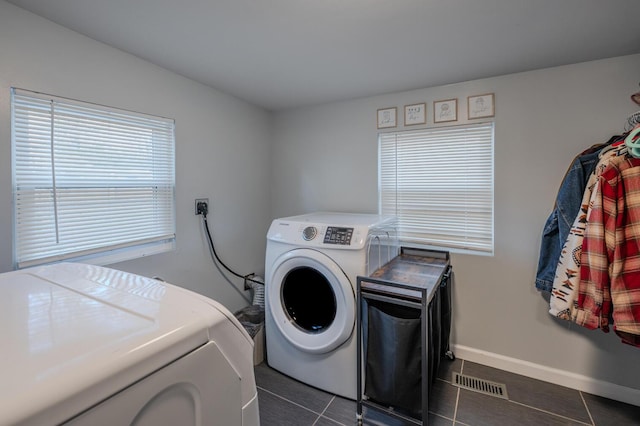 clothes washing area with washing machine and dryer and dark tile patterned floors