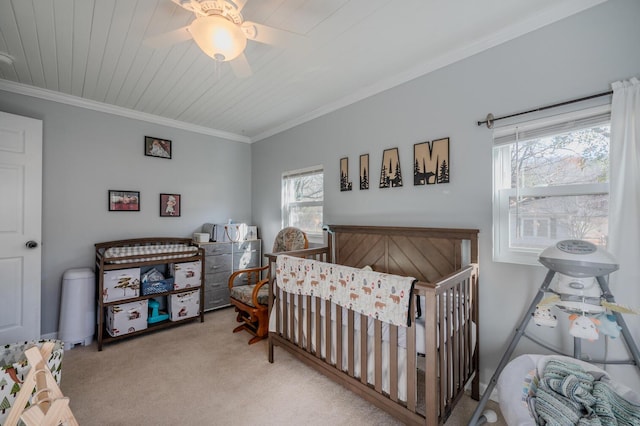 carpeted bedroom with ceiling fan, crown molding, a nursery area, and wooden ceiling