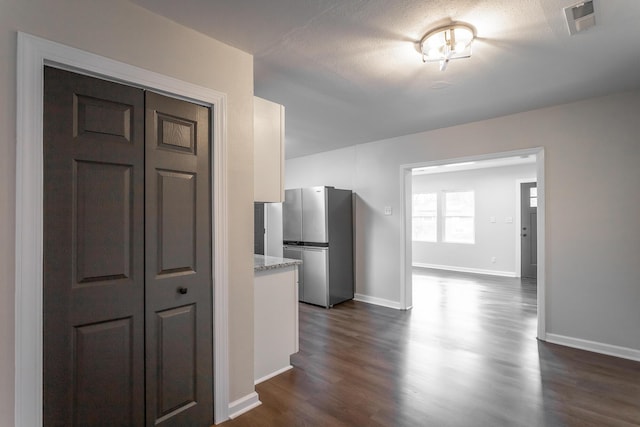 corridor with a textured ceiling and dark hardwood / wood-style flooring