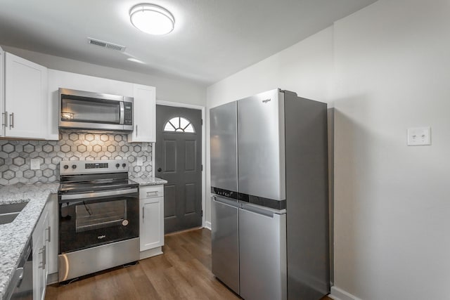 kitchen featuring white cabinets, stainless steel appliances, light stone counters, and dark wood-type flooring