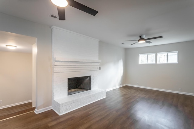 unfurnished living room with a fireplace, dark hardwood / wood-style floors, and ceiling fan