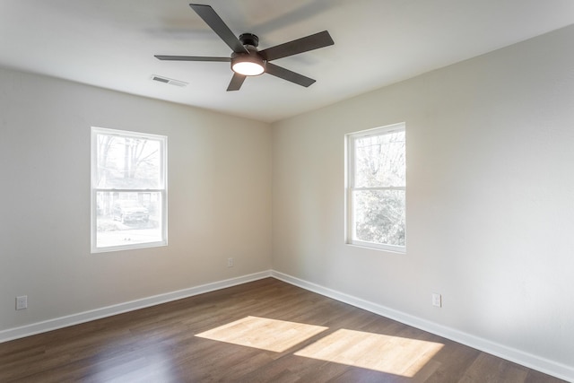 spare room featuring ceiling fan, a healthy amount of sunlight, and dark hardwood / wood-style flooring