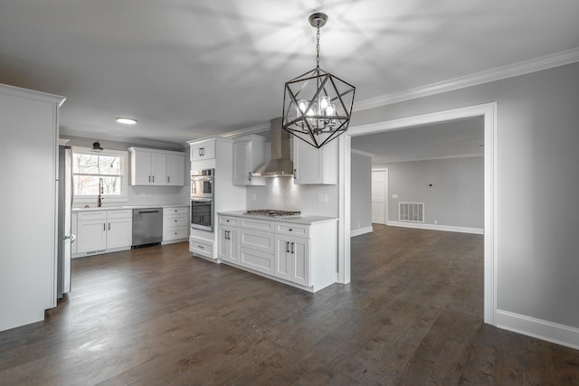 kitchen featuring appliances with stainless steel finishes, backsplash, wall chimney range hood, decorative light fixtures, and white cabinetry