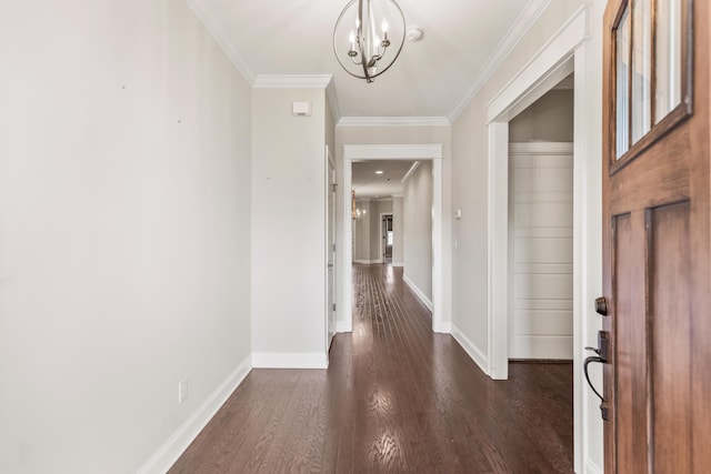 hallway featuring a notable chandelier, dark hardwood / wood-style flooring, and ornamental molding