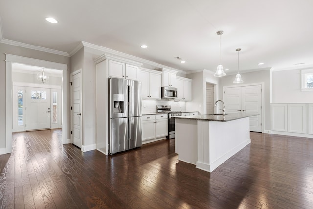 kitchen featuring appliances with stainless steel finishes, dark hardwood / wood-style floors, a wealth of natural light, and a kitchen island with sink