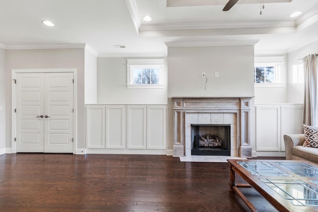 living room featuring dark hardwood / wood-style flooring, crown molding, and a tile fireplace