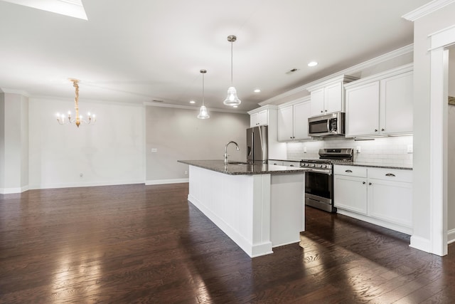 kitchen featuring pendant lighting, dark wood-type flooring, a center island with sink, appliances with stainless steel finishes, and white cabinetry