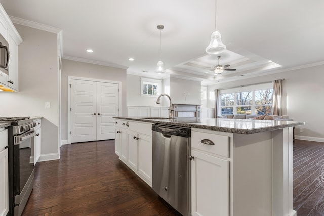 kitchen with white cabinets, a center island with sink, sink, dark hardwood / wood-style floors, and appliances with stainless steel finishes