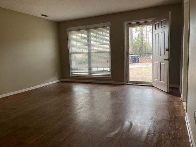 empty room with dark hardwood / wood-style floors and a textured ceiling