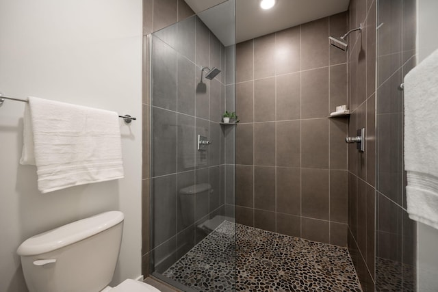 bathroom featuring tiled shower and toilet